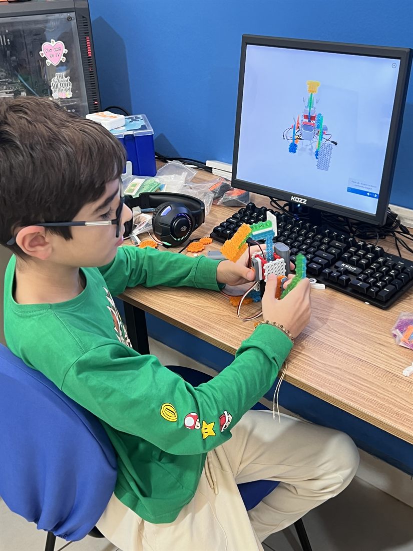 Aluno montando um robô na aula de robótica